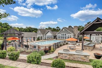 An outdoor pool with tables and umbrellas at the enclave at woodbury apartments